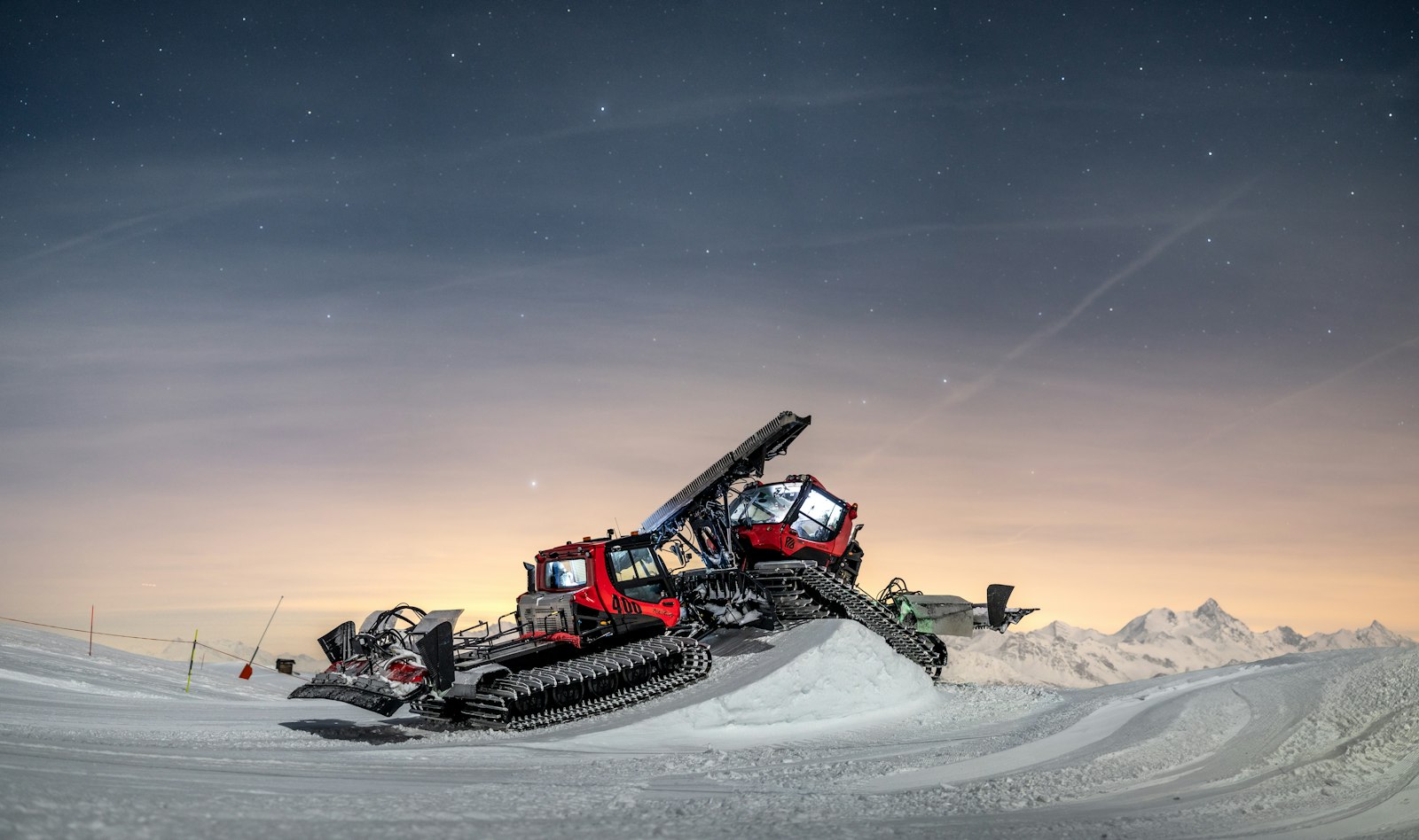 Snow groomer working a slope at dusk